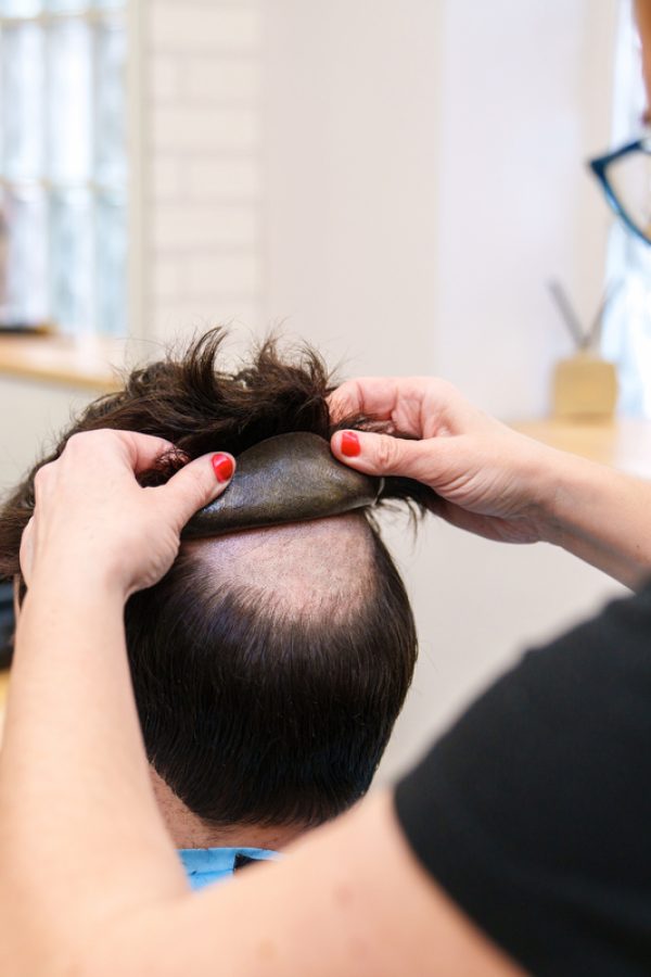 Professional fitting a natural hair prosthesis.