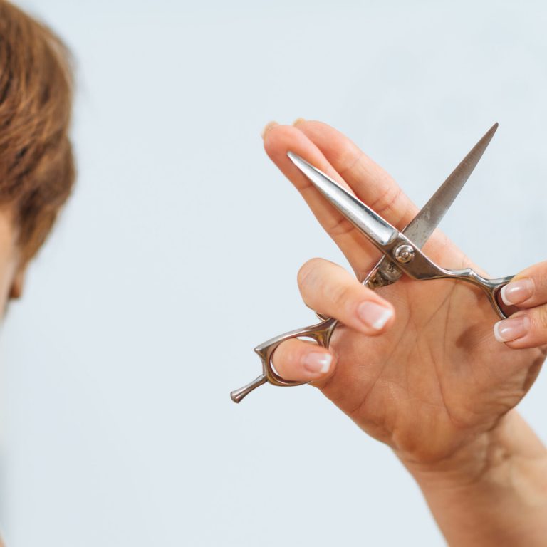 Mano de un peluquero sosteniendo unas tijeras